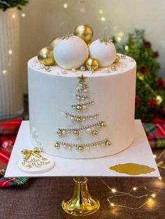 a white cake decorated with gold ornaments and baubles on top is sitting on a table