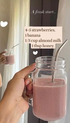 a person holding a glass jar filled with smoothie next to a sign that says, 4 - 5 strawberries i banana 1 / 3 cups almond almond milk it's tip honey