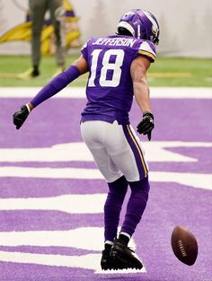 a football player is running with the ball in his hand while wearing purple and white