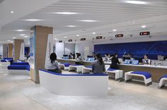 several people are sitting at computers in a large room with blue and white accents on the walls