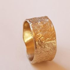 Organic form meets expert craftsmanship with this stunning solid 18K gold women’s wedding band. A subtle yet sensational statement, this piece has an apparent weight and impressive width with naturally undulating sides and a rough-textured surface.Each ring is handcrafted and one of kind just like the singular union they represent.◈ DETAILSWeight: 6gWidth: 12-13mm / 0.47''- 0.51''Thickness: 1.1-1.5mm / 0.39''- 0.06''◈ MATERIAL18K Solid Gold◈ ALSO AVAILABLE IN 14K Yellow, Rose, or White Gold◈ ENG Modern Wide Band Ring With Hammered Detail, Hammered Thick Band Wide Ring For Promise, Hammered Wide Band Ring For Promise, Hammered Wide Band Ring As Gift, Modern Hammered Gold Ring, Hand Forged Wide Band Ring For Gift, Hand Forged Wide Band Ring As Gift, Hand Forged Thick Band Wide Ring, Hammered Yellow Gold Round Bands