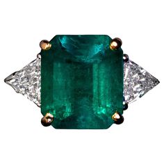 This contemporary platinum and gold ring features a 3.96 carat Colombian emerald of a vivid bluish green color flanked by two trillion cut diamonds. The emerald has good color saturation and sparkle. The actual color of the emerald is more vivid and more saturated than shown on the website. Total emerald weight is 3.96 carats. Estimated combined diamond weight is 0.90 carat. The ring is marked with 950 platinum standard and Austrian butterfly assay mark for Vienna. The ring is accompanied by the American Gemological Laboratories Prestige report 1141663 for the emerald. Ring size 5 (16 mm) resizable Emerald Diamond Engagement Ring, Emerald Ring Engagement Diamond, Colombian Emeralds, Bluish Green, Emerald Diamond, Jewelry Rings Engagement, Diamond Engagement Ring, Vienna, Ring Verlobung