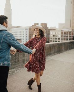 a man and woman holding hands while walking across a bridge