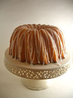 a bundt cake covered in icing on a white platter with a decorative design