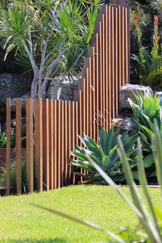 a wooden fence in the middle of a garden with succulents and trees