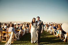 a bride and groom walking down the aisle after their wedding ceremony at an outdoor venue