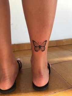 a woman's legs with a butterfly tattoo on her left leg and right foot