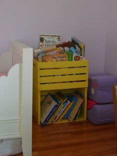 there is a yellow crate with books on it next to a purple chair and wall