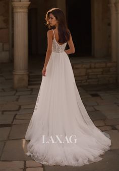 a woman in a white wedding dress standing on a stone walkway with her back to the camera