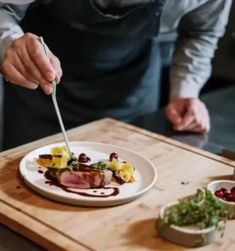 a man in an apron is cutting up food on a white plate with a knife and fork