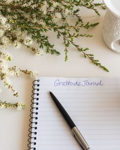 a notepad with writing on it next to a cup of coffee and some flowers