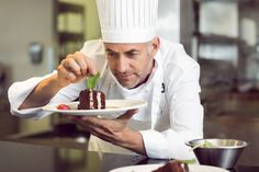 a man in a chef's hat is holding a plate with some food on it