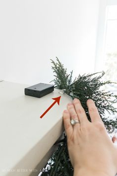 someone is placing their hand on the edge of a table with a christmas tree in front of them