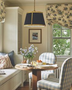 a dining room table with two chairs and a bench in front of the window,