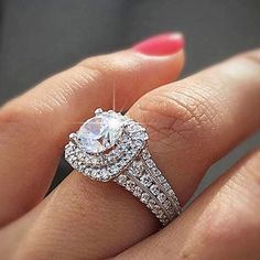 a woman's hand with a diamond ring on top of her finger and the other hand holding an engagement ring