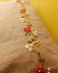 a close up of a pillow on a bed with flowers embroidered on the front and back