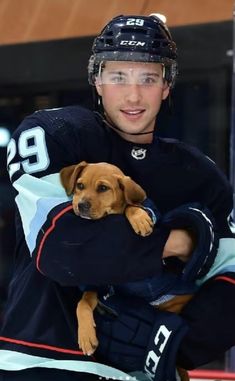 a man holding a dog in his arms while wearing a hockey uniform on the ice