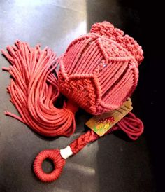 a red knitted hat sitting on top of a table next to a cord and tag