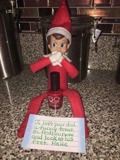 an elf sitting on top of a counter next to a sign