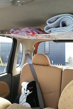 there is a stuffed bear in the back seat of a car with surfboards on top