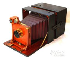 an old fashioned camera sitting on top of a wooden stand