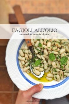 a white bowl filled with pasta and garnished with mint leaves on a blue and white plate