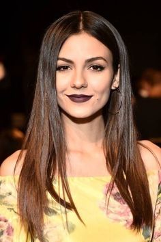 a woman with long brown hair wearing a yellow top and purple lipstick on her lips