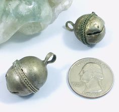 two small silver bells sitting next to a dime