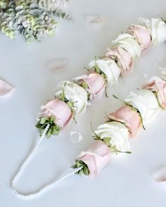 flowers and pearls are arranged in the shape of an arrow on a white tablecloth