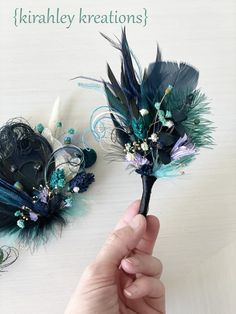 a hand holding a flower with feathers attached to it