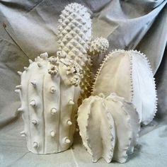 three white ceramic cactus sculptures sitting on top of a table