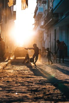 children playing on the street at sunset in an alleyway with cars and people walking