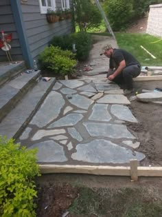 a man working on an outdoor patio with flagstone pavers laid out in front of the house