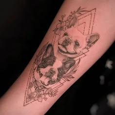 a small dog tattoo on the arm with flowers and leaves around it, in front of a woman's leg