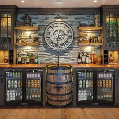 a large clock mounted to the side of a wall next to a wooden barrel filled with drinks