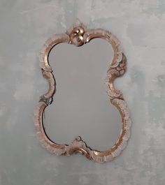 a mirror that is on the wall in front of a gray background with gold accents