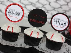 cupcakes with white frosting and red sprinkles are on a black plate