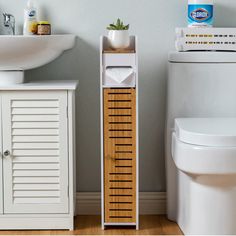 a white toilet sitting next to a wooden cabinet