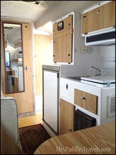 a small kitchen with white appliances and wood cabinets in an airstreame style home