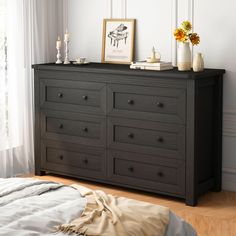 a bedroom with a bed, dresser and pictures on the wall