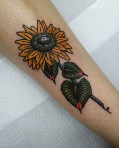 a sunflower tattoo on the arm with green leaves and an eyeball in it