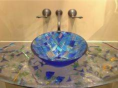 a glass bowl sink sitting on top of a counter next to a faucet