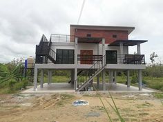 a two story house sitting on top of a dirt field