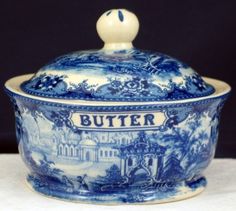 a blue and white tureen with the word butter on it's lid sitting on a table