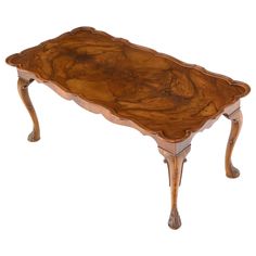 a wooden table with carved legs and an oval shaped top, on a white background