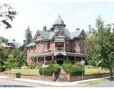 a large red brick house with many windows and lots of greenery on the front