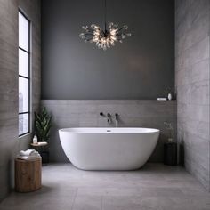 a large white bath tub sitting under a chandelier in a bathroom next to a window