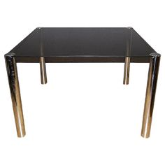 a glass table with metal legs and a black top is shown against a white background