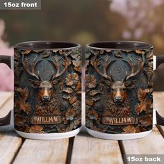 two coffee mugs sitting on top of a wooden table with an image of a deer's head