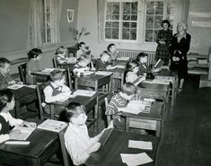 an old black and white photo of children at desks